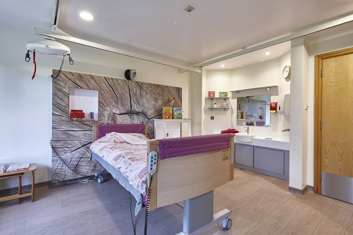 A care bedroom with a profiling bed, ceiling hoist and ensuite, ready for the next stay