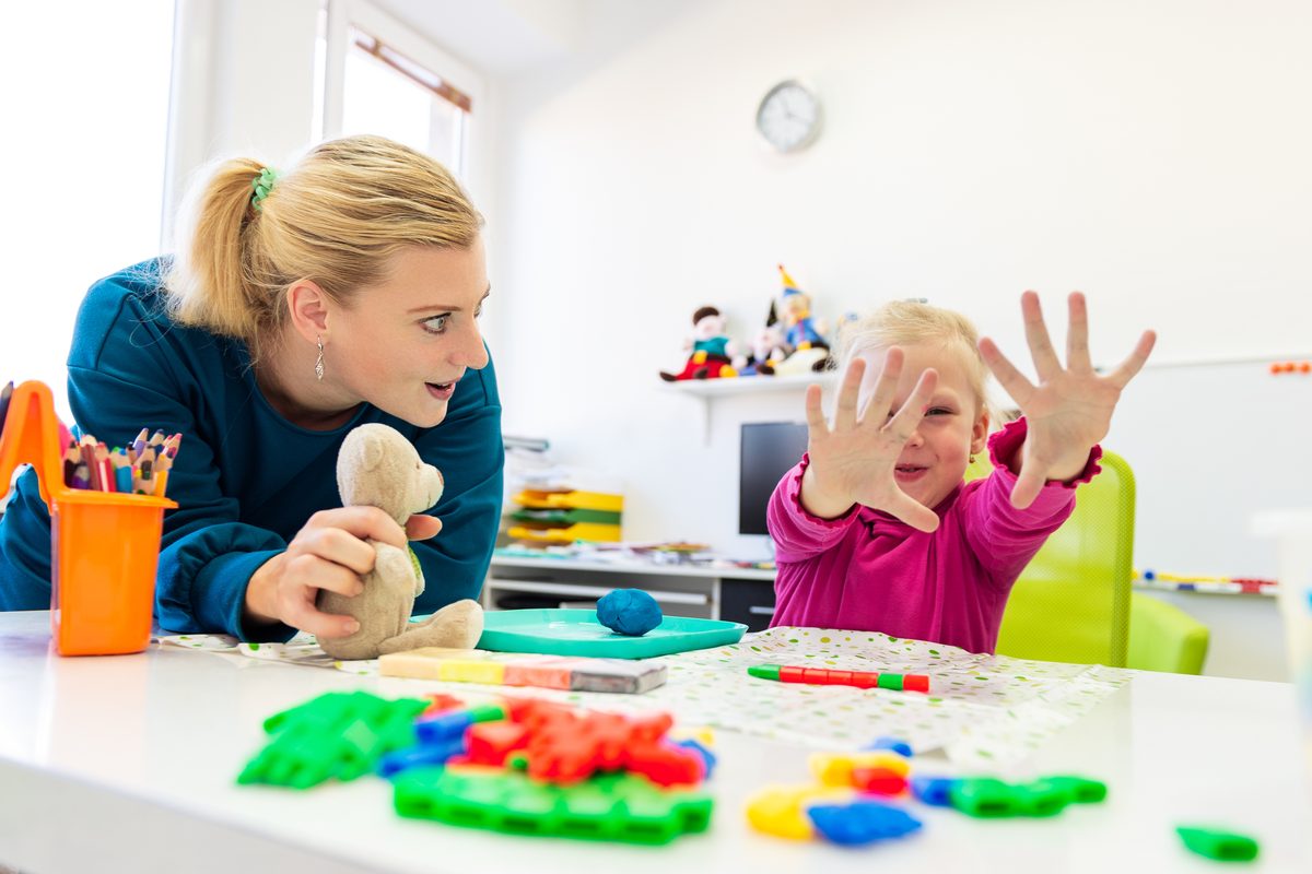 An adult and a child playing together at a table during a support session