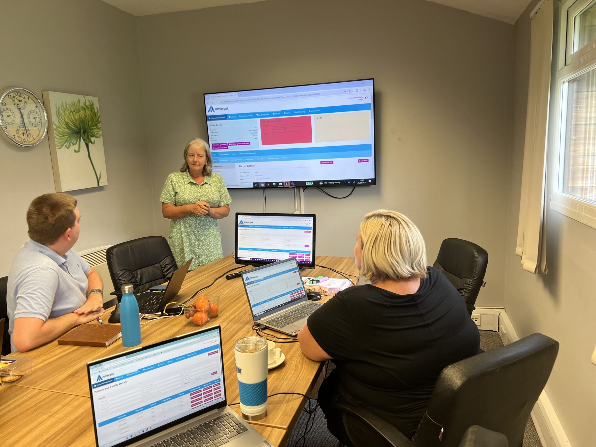 An Ameryst trainer running a training session with a care team, with the software on a large screen and on laptops.